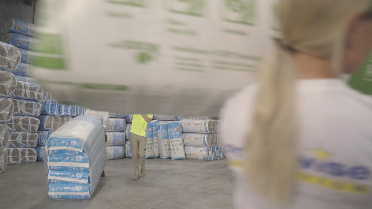 Pricewise staff carrying wall insulation rolls through the warehouse